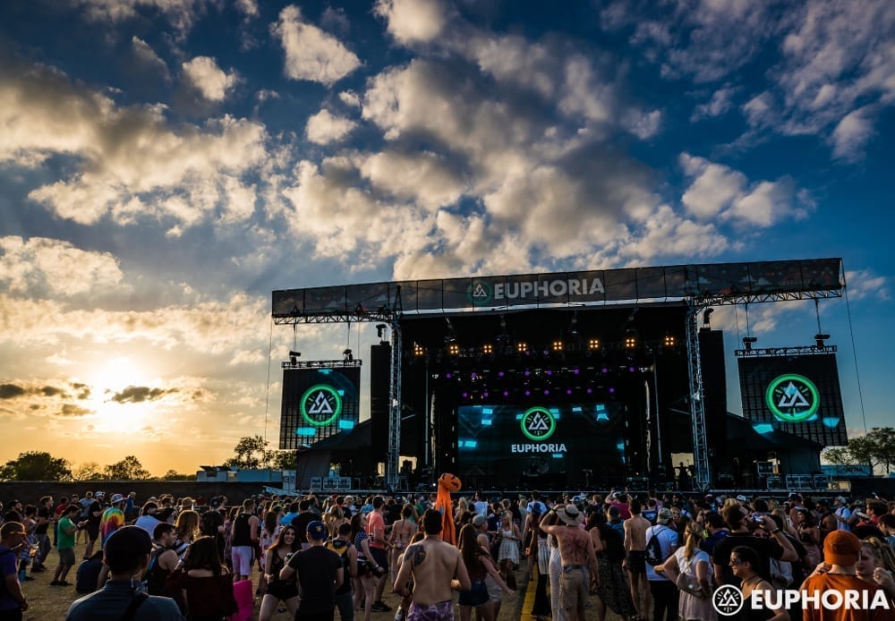 Outdoor Euphoria Fest stage at dusk with clouds in the sky and crowds of people