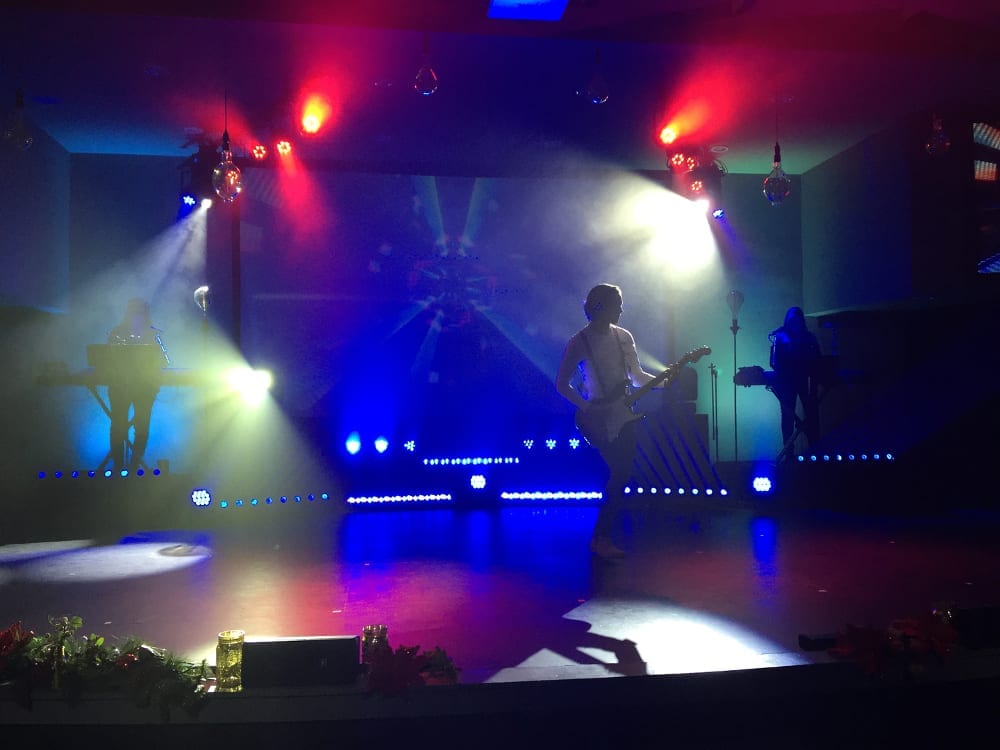 Worship musicians performing on stage with blue and red lights