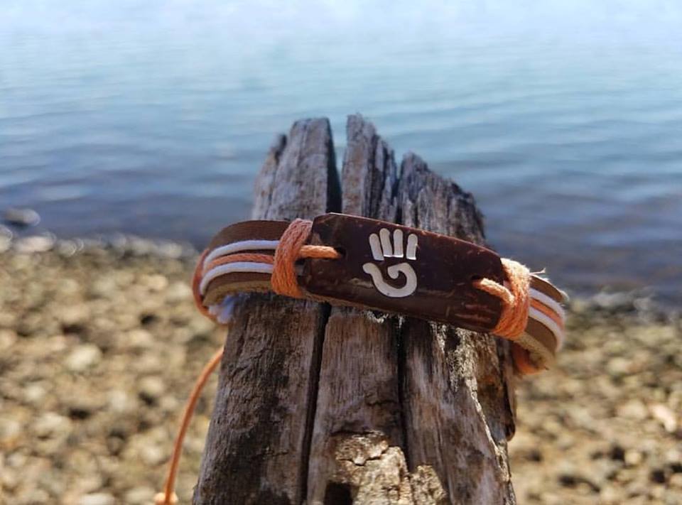 Brown bracelet with hand design wrapped around a branch by the waterfront