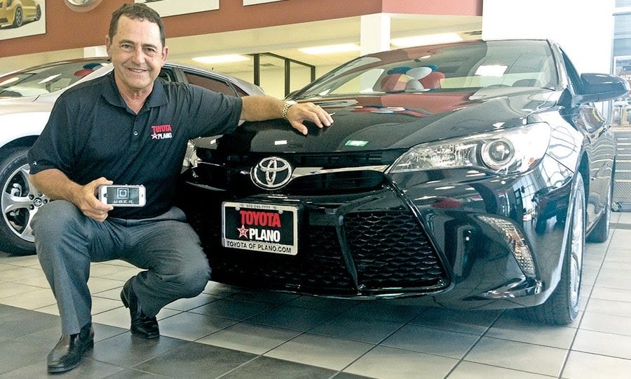 A dealership employee posing with a branded car