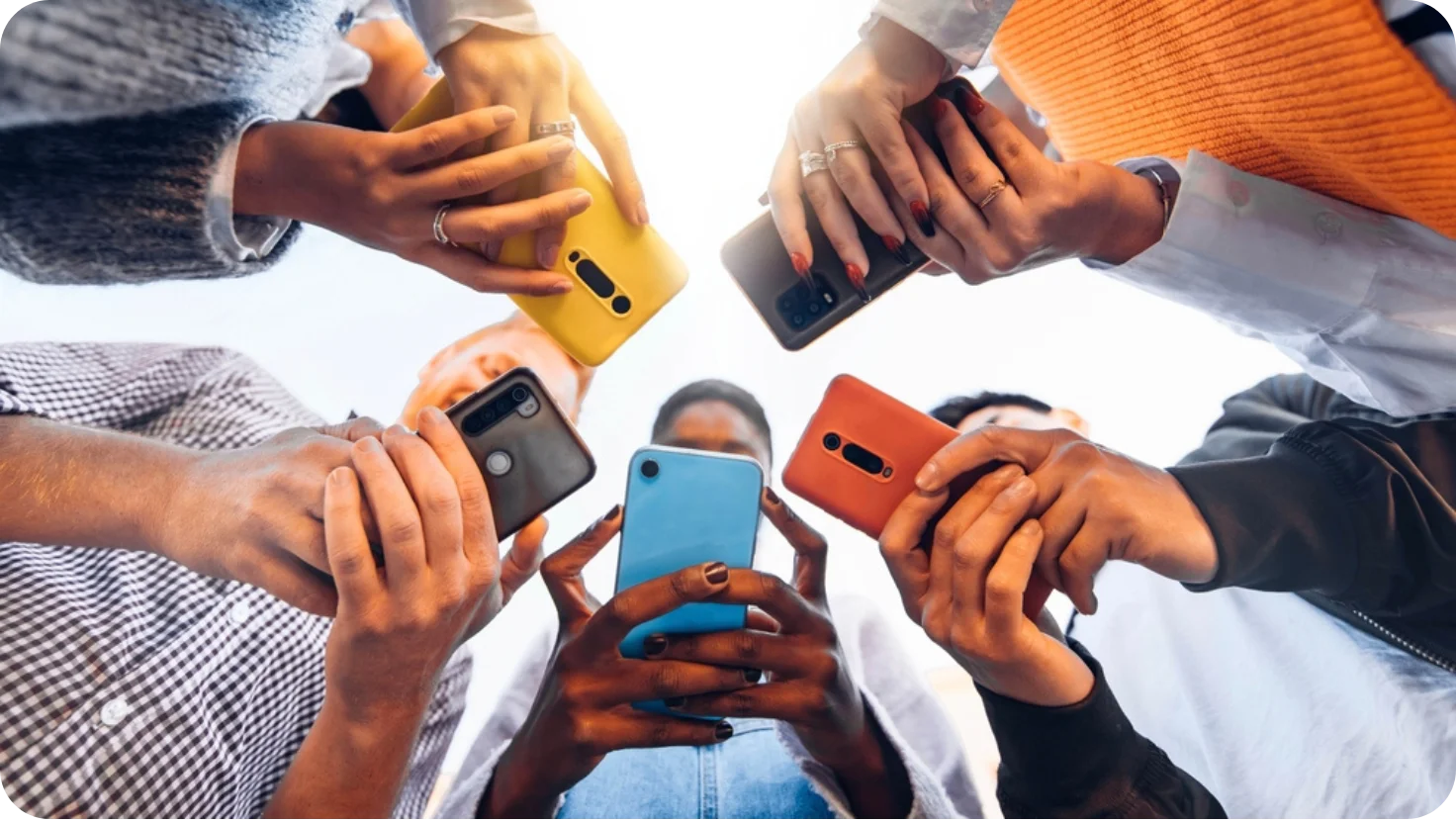 Group of friends using smartphones together outdoors